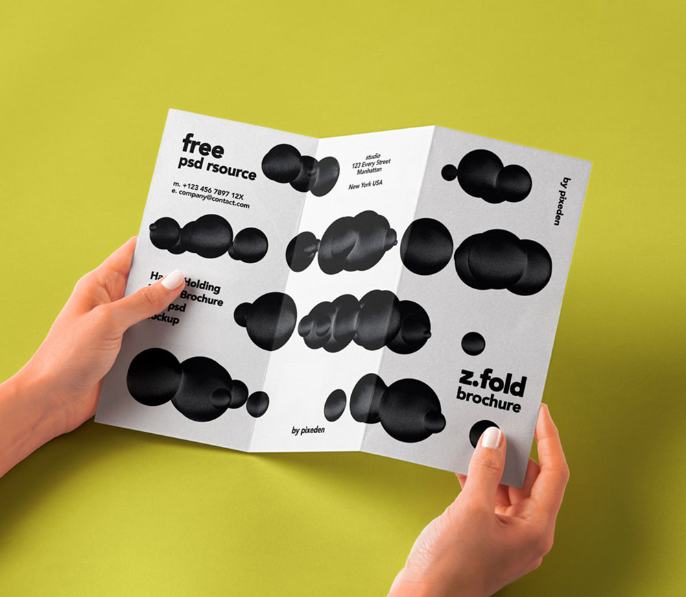 Free Hand Holding Folded Brochure Mockup PSD
